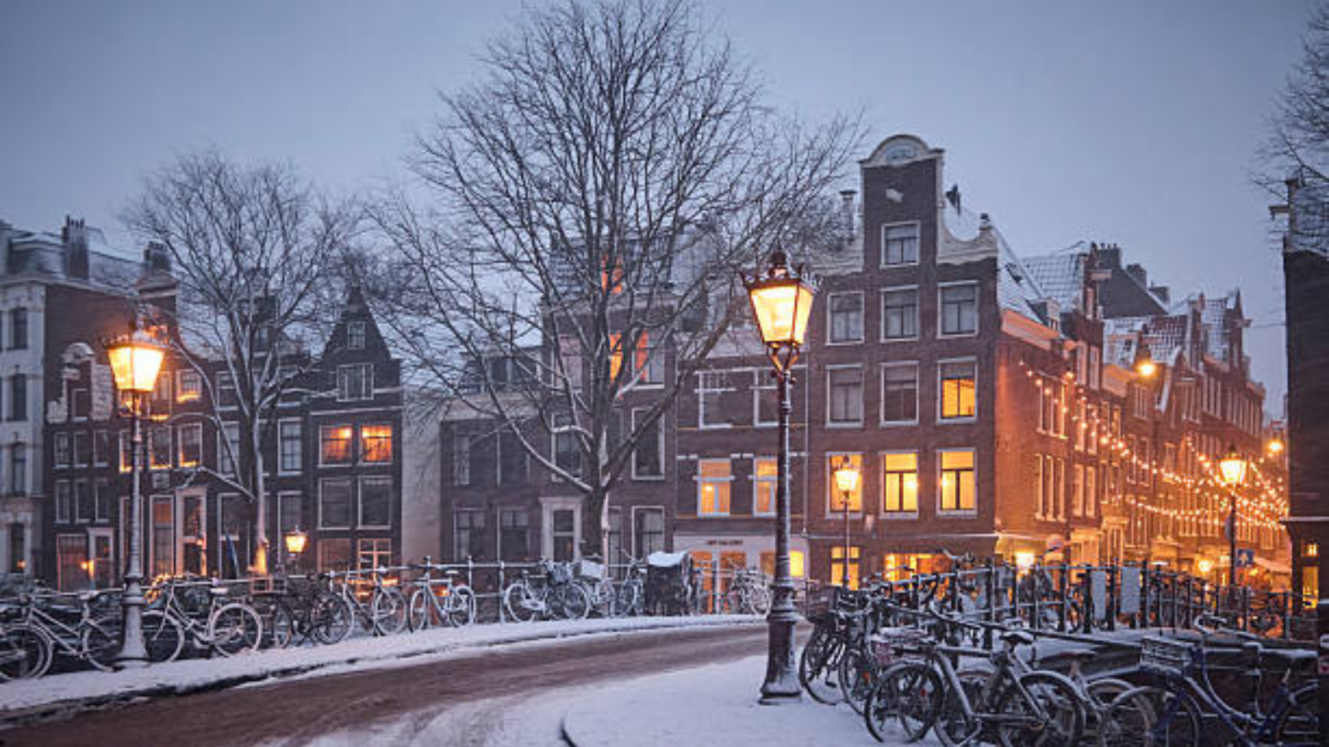 Dusk view of canal buildings with parked bikes and street lamps